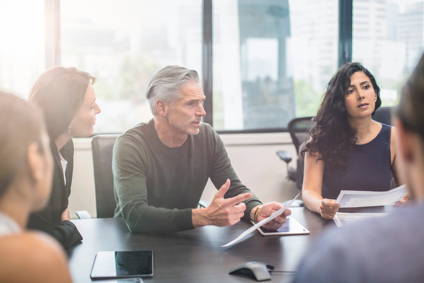 Mature businessman talking to his colleagues on a meeting at the office.